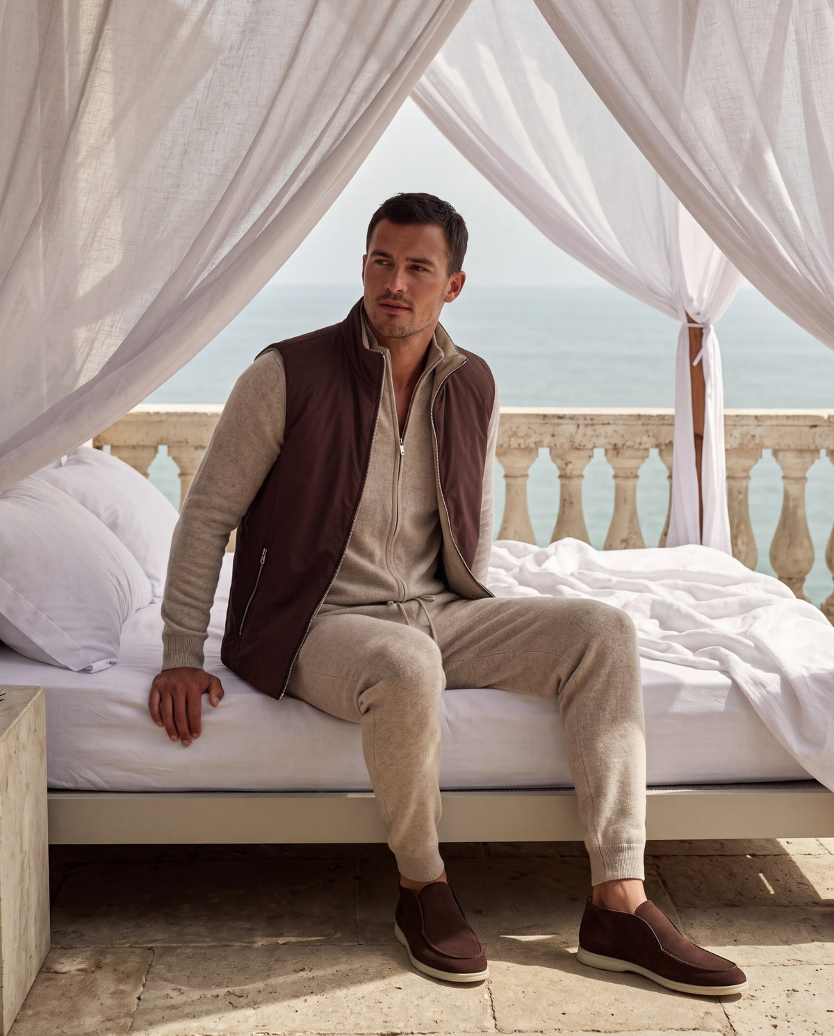 Espresso Montreux gilet, oatmeal knit two-piece set and chocolate suede loafers on a softly lit Mediterranean terrace.